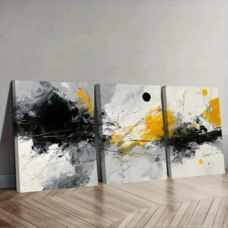 Set of three abstract paintings with yellow and black on a gray wall.