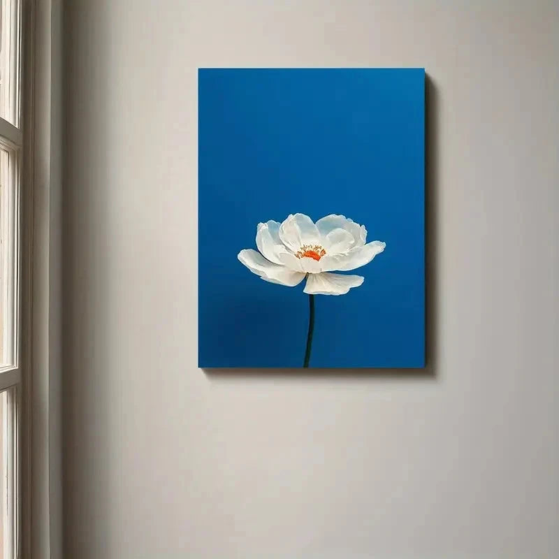 Canvas print of a white flower on a blue background hanging on a wall.