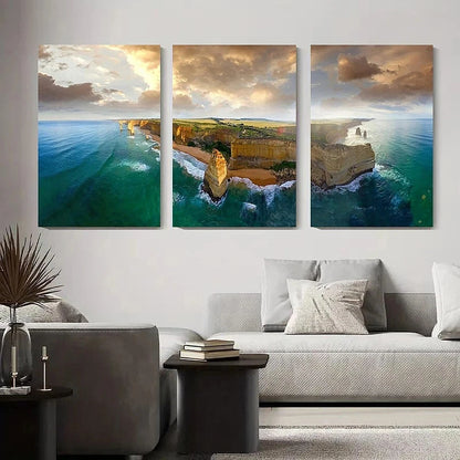 Three-panel wall art of a coastal landscape above a living room with a sofa and coffee table.