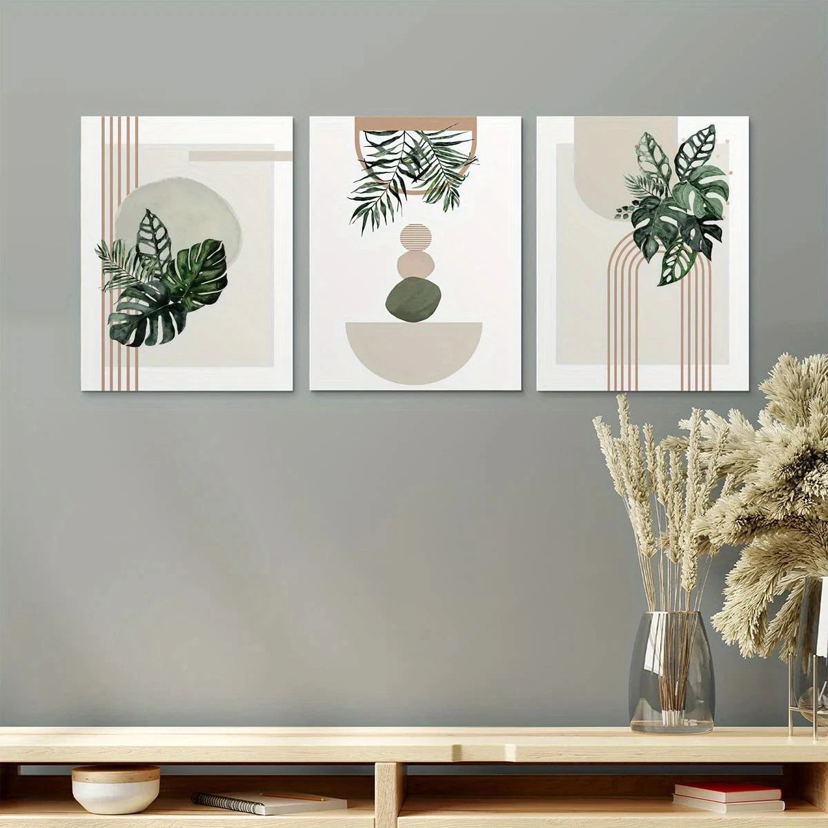 Three abstract metal art prints with green leaves on a gray wall.