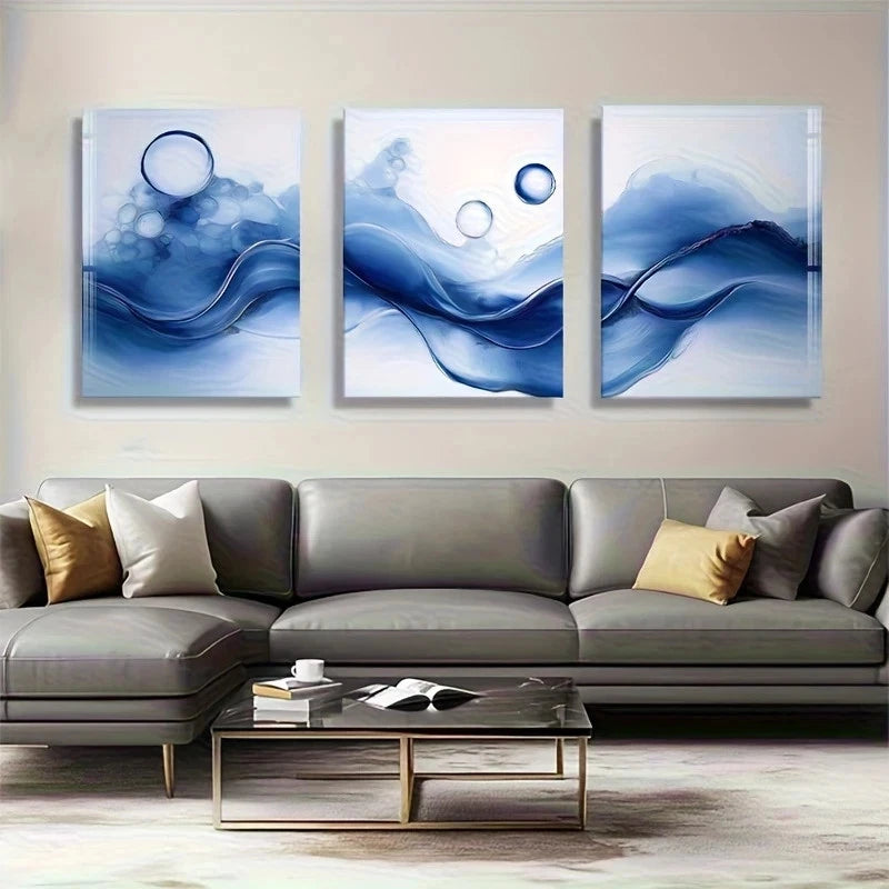 Three abstract blue artworks above a gray sofa in a living room.