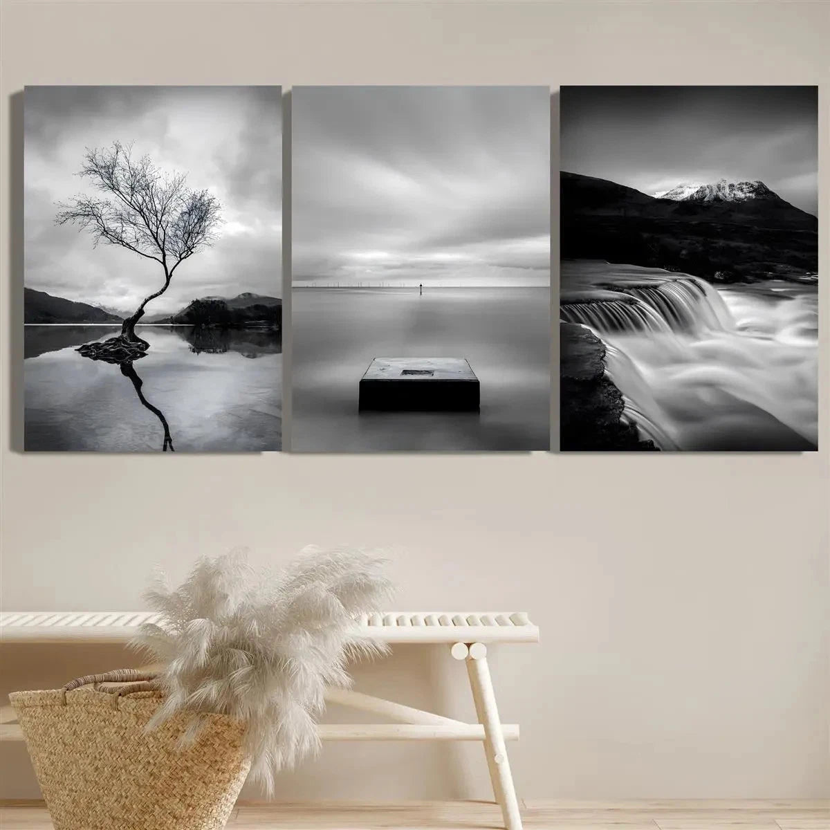 Three black and white landscape paintings on a wall above a bench.