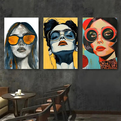 Three colorful artworks of women wearing sunglasses on a dark wall.