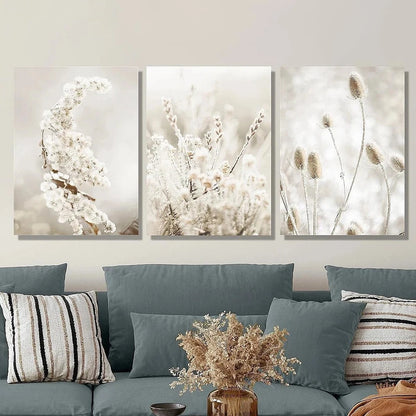 Three framed artworks of floral arrangements on a wall above a sofa with decorative pillows.