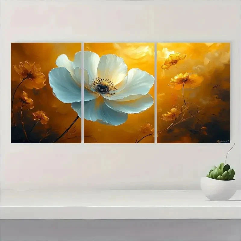 Triptych floral painting with a large white flower on a yellow background, displayed on a wall above a white shelf with a small plant.