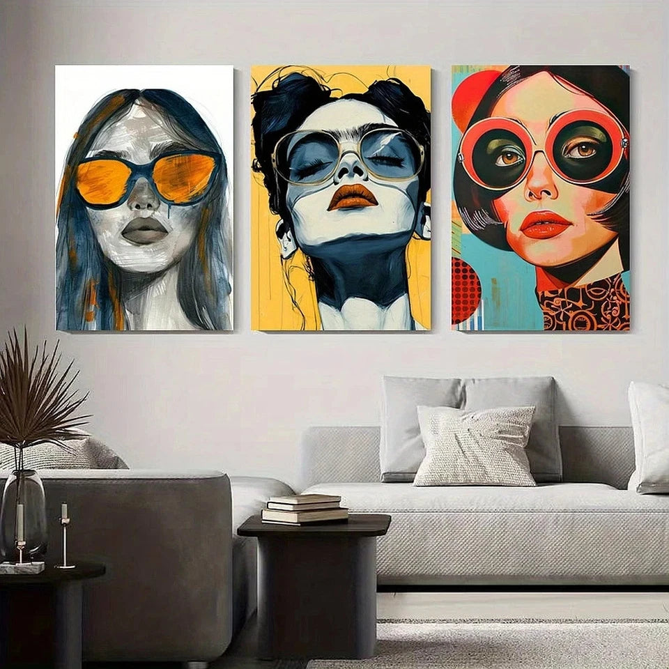 Three colorful portraits of women with sunglasses on a wall above a sofa.